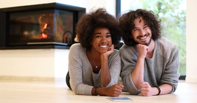 beautiful young multiethnic couple lying on the floor of their luxury home in front of fireplace at autumn day