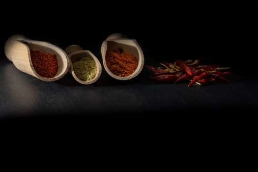 Low key photo of different types of ground chili with dried peppers