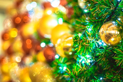 Selective focus Christmas tree with holiday gold ball and lights with copy space on blurred bokeh background.