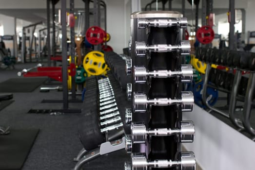 many dumbbells and other sport's equipments in gymnasium on blurred background