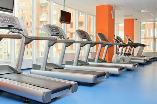 Gym with windows and running machines in fitness center