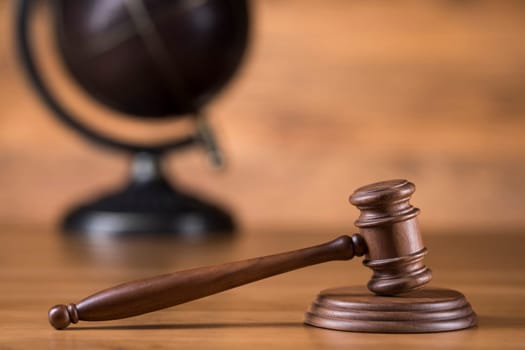 Law theme, mallet of judge, wooden gavel, globe background