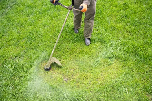 Mowing the grass with a lawn mower. Garden work concept background.