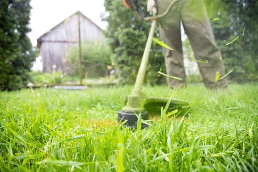 Mowing the grass with a lawn mower. Garden work concept background.