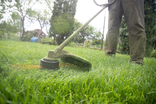 Mowing the grass with a lawn mower. Garden work concept background.