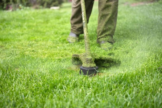 Mowing the grass with a lawn mower. Garden work concept background.