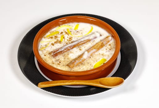 Dish of rice pudding with grated cinnamon, with lemon scratches. on plate and wooden spoon