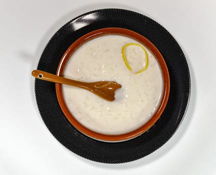 Dish of rice pudding with lemon scratches and with spoon