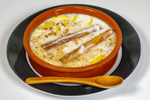Dish of rice pudding with grated cinnamon, with lemon scratches. on plate and wooden spoon