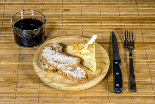 Spanish tortilla skewer presented in typical ration of Spain, With bread and a glass of red wine