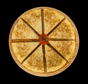 A triangle of potato Spanish omelette on a plate isolated background in black color