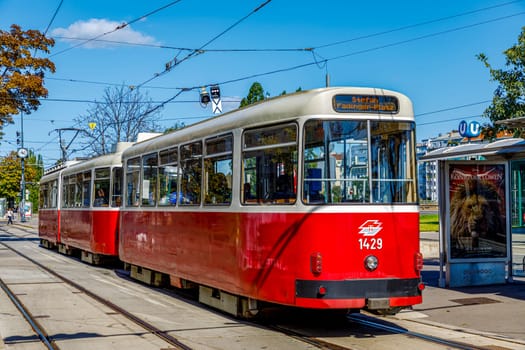 Vienna, Austria - September 16, 2019: Original local Vienna tram is going by schedule to station (Strassenbahn Haltestelle) on Karlsplatz. With history dating back to mid-19th century. It is located in centre of Vienna