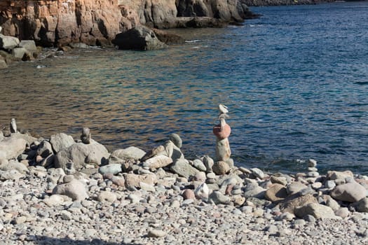 Stone pyramid on the beach in the sand in front of the sea