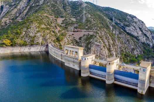 View of hydro-electric power station and a highway. Dam at Segre river, Oliana, Spain, Europe. Mountain peaks landscape