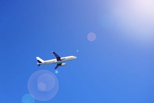 Plane flying high in sky. View to air liner flying in blue sky. Airplane seen in blue sky. Aerial panorama with aircraft in cloudless sky. Flying air liner in sunny rays