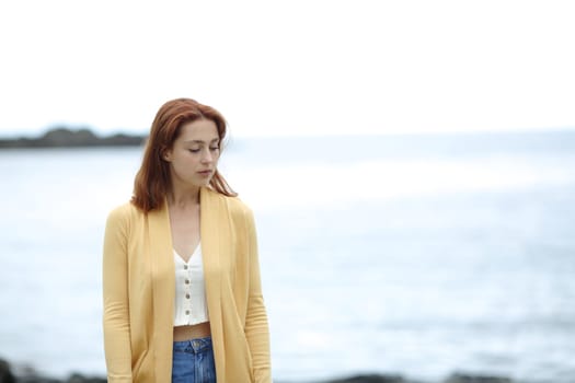 Sad pensive woman walking alone on the beach