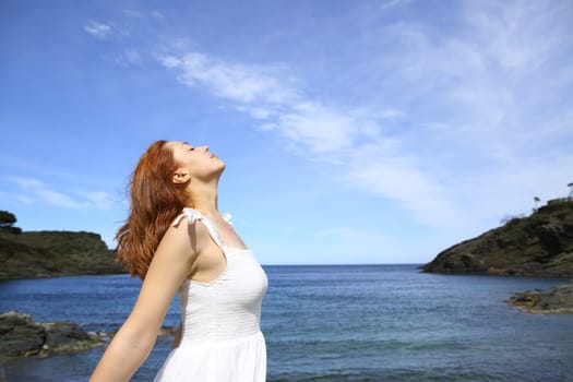 Happy tourist on the beach celebrating vacation raising arms
