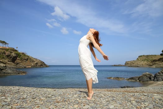 Woman in white dress breathing fresh air on the beach