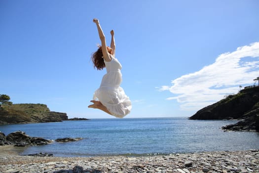 Happy tourist on the beach celebrating vacation raising arms