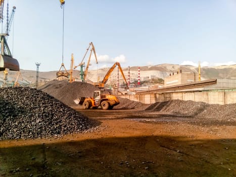 Novorossiysk, Russia - August 20, 2017: Cargo industrial port, port cranes. Loading of anthracite. Transportation of coal. Heap of coal