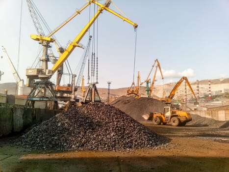 Novorossiysk, Russia - August 20, 2017: Cargo industrial port, port cranes. Loading of anthracite. Transportation of coal. Heap of coal
