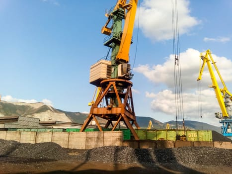 Novorossiysk, Russia - August 20, 2017: Cargo industrial port, port cranes. Loading of anthracite. Transportation of coal. Heap of coal