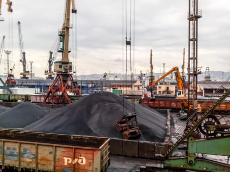 Novorossiysk, Russia - August 20, 2017: Cargo industrial port, port cranes. Loading of anthracite. Transportation of coal. Heap of coal