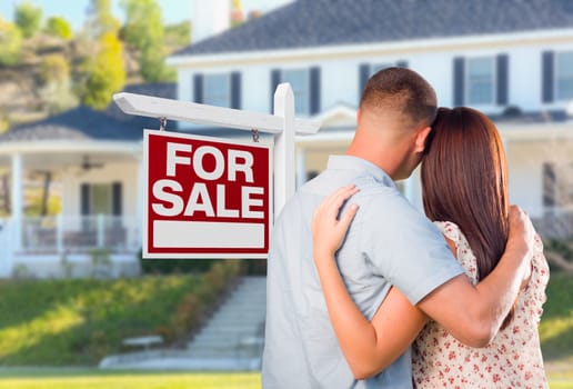 Military Couple Looking At House with For Sale Real Estate Sign In Front.