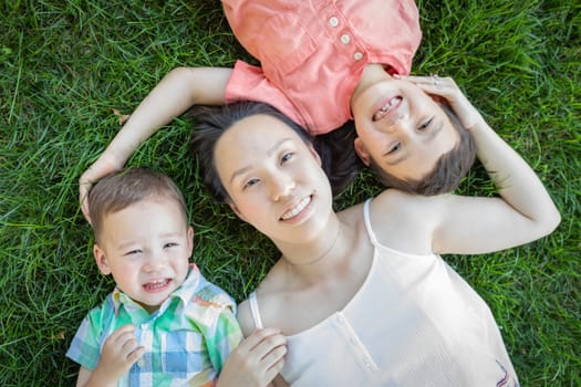 Chinese Mother and Mixed Race Children Laying On Grass.