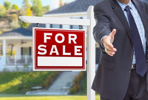 Male Agent Reaching for Hand Shake in Front of For Sale Sign and House.
