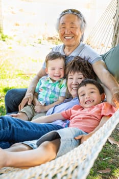 Chinese Grandparents In Hammock with Mixed Race Children.