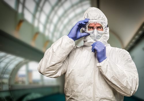 Man With Intense Expression Wearing HAZMAT Protective Clothing Inside Building.