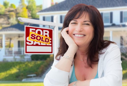 Middle Aged Woman In Front of House with Sold For Sale Real Estate Sign In Yard.