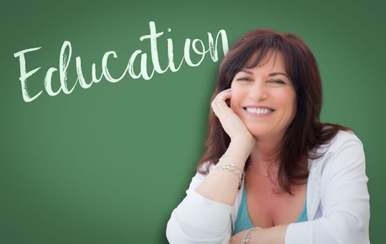 Education Written On Green Chalkboard Behind Smiling Middle Aged Woman.