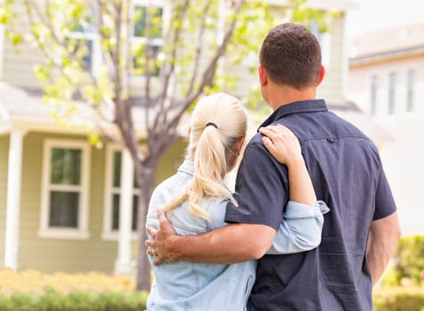 Happy Caucasian Couple Facing Front of House.