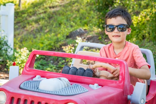 Young Mixed Race Chinese and Caucasian Boy Wearing Sunglasses Playing In Toy Car