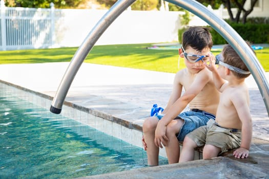 Young Mixed Race Chinese and Caucasian Brothers Wearing Swimming Goggles Playing At The Pool