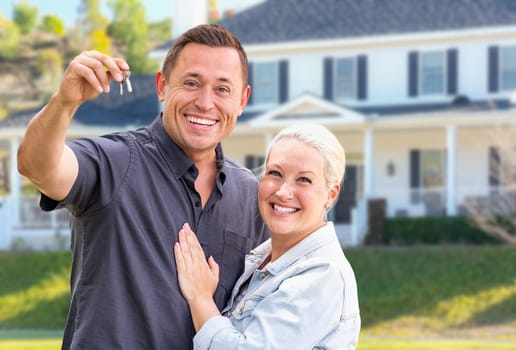 Young Adult Couple With House Keys In Front of Beautiful Home.