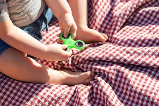 Baby Boy Sitting on Picnic Blanket Playing With Fidget Spinner
