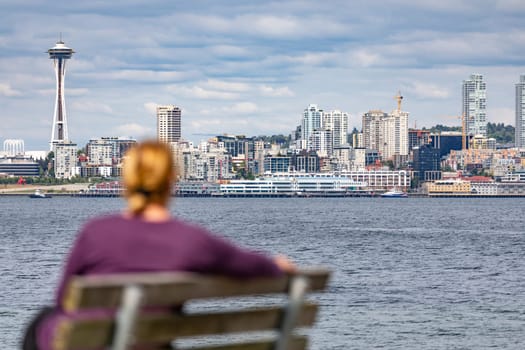 Woman Sitting on Bench Looking At The Seattle, Washington Skyline