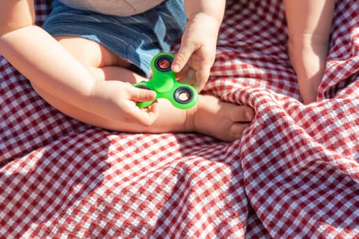 Baby Boy Sitting on Picnic Blanket Playing With Fidget Spinner