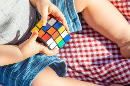 Baby Boy Sitting on Picnic Blanket Playing With Cube Puzzle