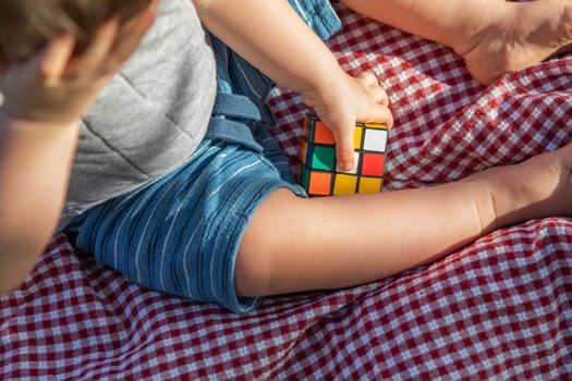 Baby Boy Sitting on Picnic Blanket Playing With Cube Puzzle