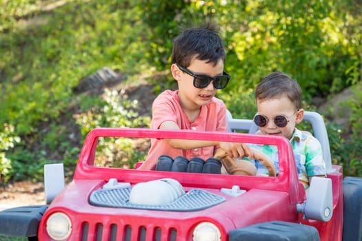 Young Mixed Race Chinese and Caucasian Brothers Wearing Sunglasses Playing In Toy Car