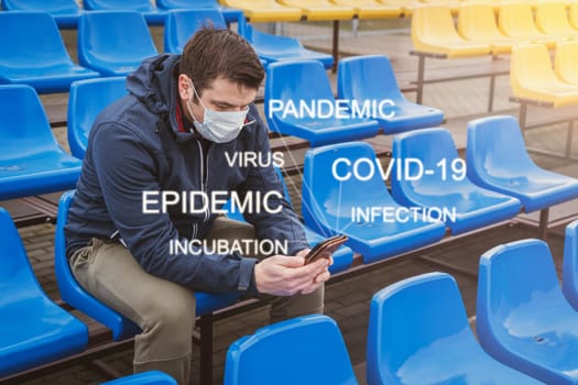 Man wears a mask against the coronavirus while reading a messages or news about global pandemic on his cell phone.