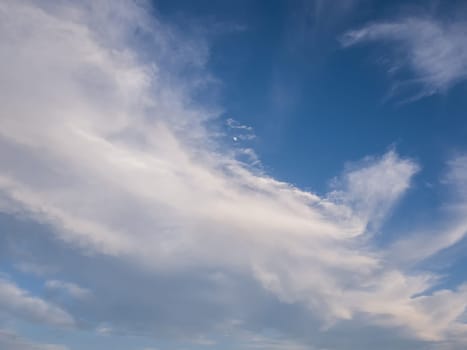 Tranquil cloudscape and the tiny moon on the blue sky. Fluffy white clouds aerial composition. Misty overcast cumulus shapes, abstract nebula textures. Air fresheners, celestial beauty.