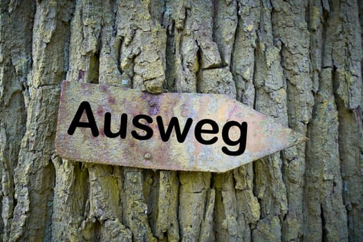 old rusty sign with the inscription way out (Ausweg) on a tree