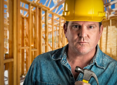 Serious Contractor in Hard Hat Holding Hammer At Construction Site.