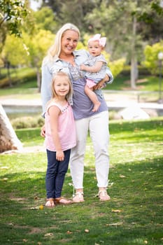 Happy Young Caucasian Mommy and Daughters Portrait In The Park.