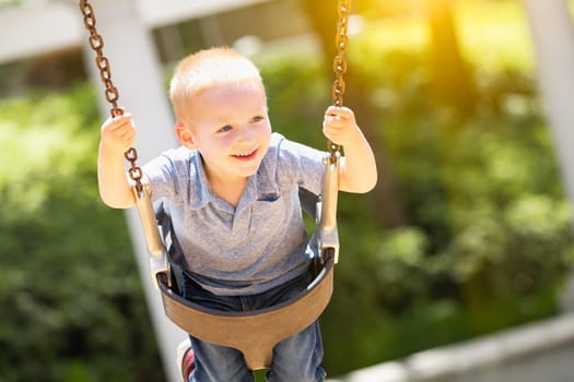 Happy Young Boy Having Fun On The Swings At The Playground.